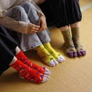 Lifestyle image of multiple people wearing Mikasayama tabi socks in different colors, seated on a tatami mat, showcasing the split-toe design and playful patterns.
