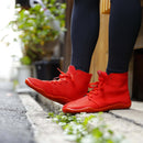 Lifestyle image of a person wearing red SPORTS JOG II tabi shoes while walking outdoors, showcasing the bold color and split-toe design.