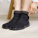 Close-up of black KAMON tabi shoes featuring a split-toe design and a sleek, understated look.