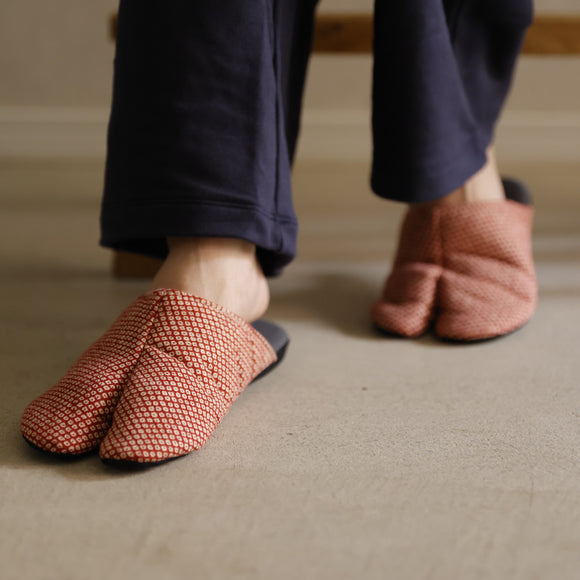 Close-up of KANOKO tabi slippers in a soft textured fabric, featuring a split-toe design and worn with dark pants.