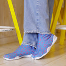 Close-up of MARU SANKAKU SHIKAKU tabi socks featuring a split-toe design and colorful geometric patterns, worn with denim pants.