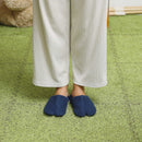 Person wearing navy PILE split-toe room shoes, standing on a grassy surface