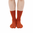 Person wearing long orange Tabi Socks " Pixel Daibutsu ", front view